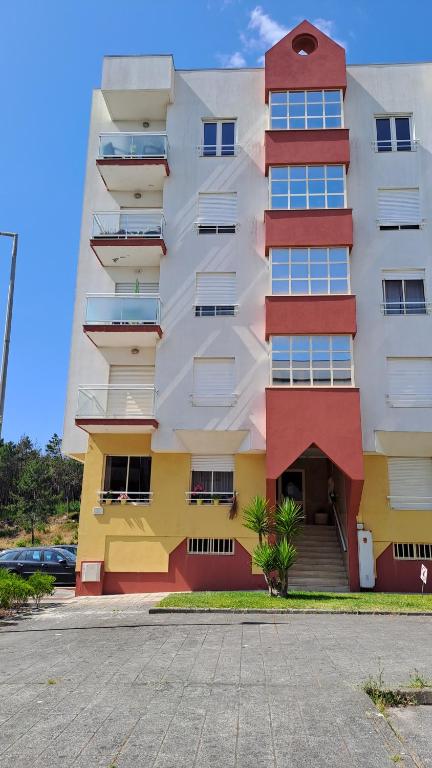 a tall apartment building with colorful balconies and a parking lot at Terra e Mar in Amorosa