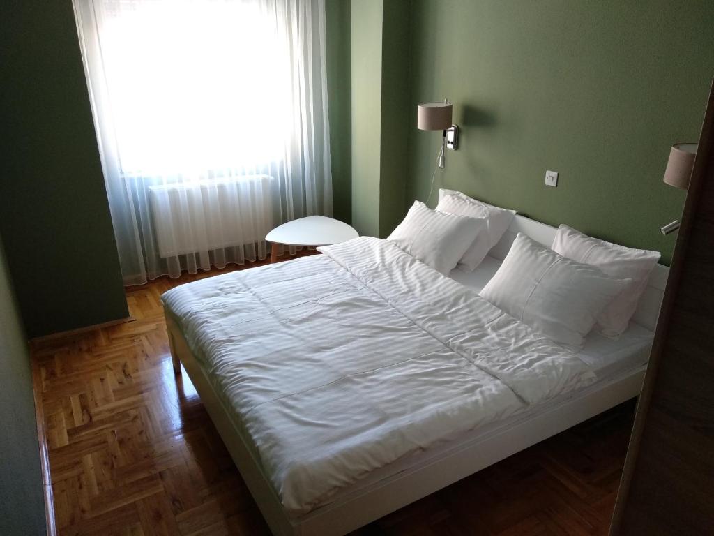 sypialnia z dużym białym łóżkiem i oknem w obiekcie Fushe Kosove Apartments w Prisztinie
