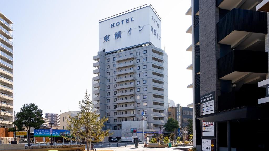 a tall white building with a ford sign on it at Toyoko Inn Kurashiki-eki Minami-guchi in Kurashiki