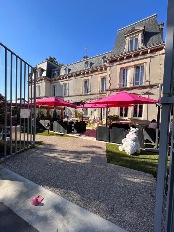 una puerta con sombrillas rosas frente a un edificio en La Demeure d'Élodie, en Épernay