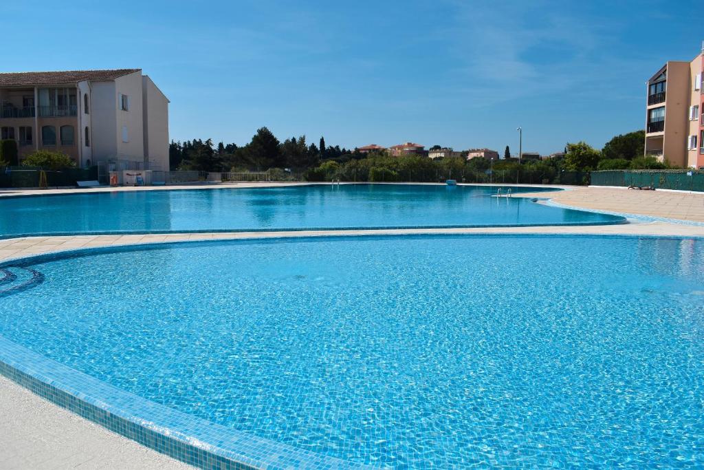 a large swimming pool with blue water at Appartement Zen à Frejus avec jardin, piscine, tennis, proche mer in Fréjus