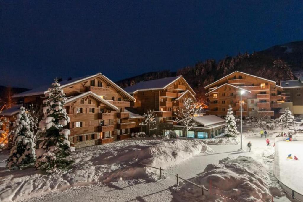 un pavillon de ski dans la neige la nuit dans l'établissement Appartement 4 pers avec piscine commune Carroz d'Araches, aux Carroz d'Arâches