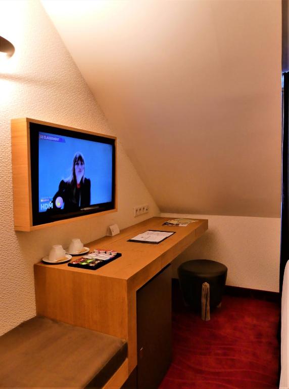 a room with a desk with a television on the wall at Le Grand Aigle Hotel & Spa**** in La Salle-les-Alpes