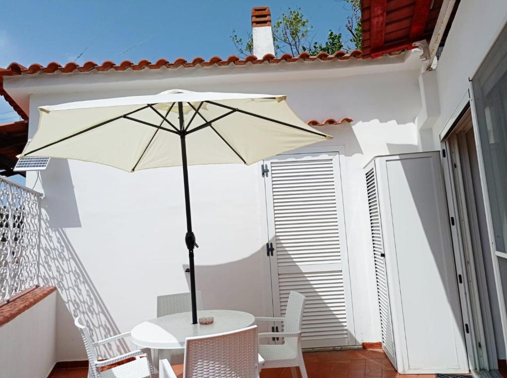 un tavolo bianco con ombrellone su un patio di La piccola grande casetta Titina a Ischia