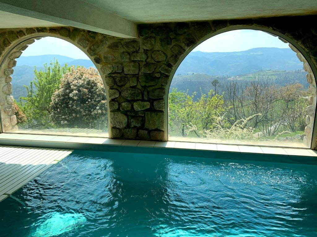 an infinity pool with two windows and a view of the mountains at Les chambres de la Bastide in Saint-Sauveur-de-Montagut