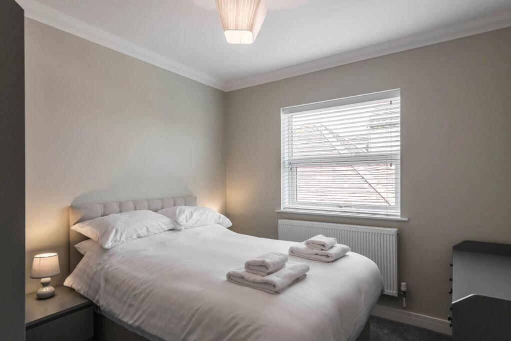 a bedroom with a white bed with towels on it at Gillian House - Charming Broadstairs apartment in Kent