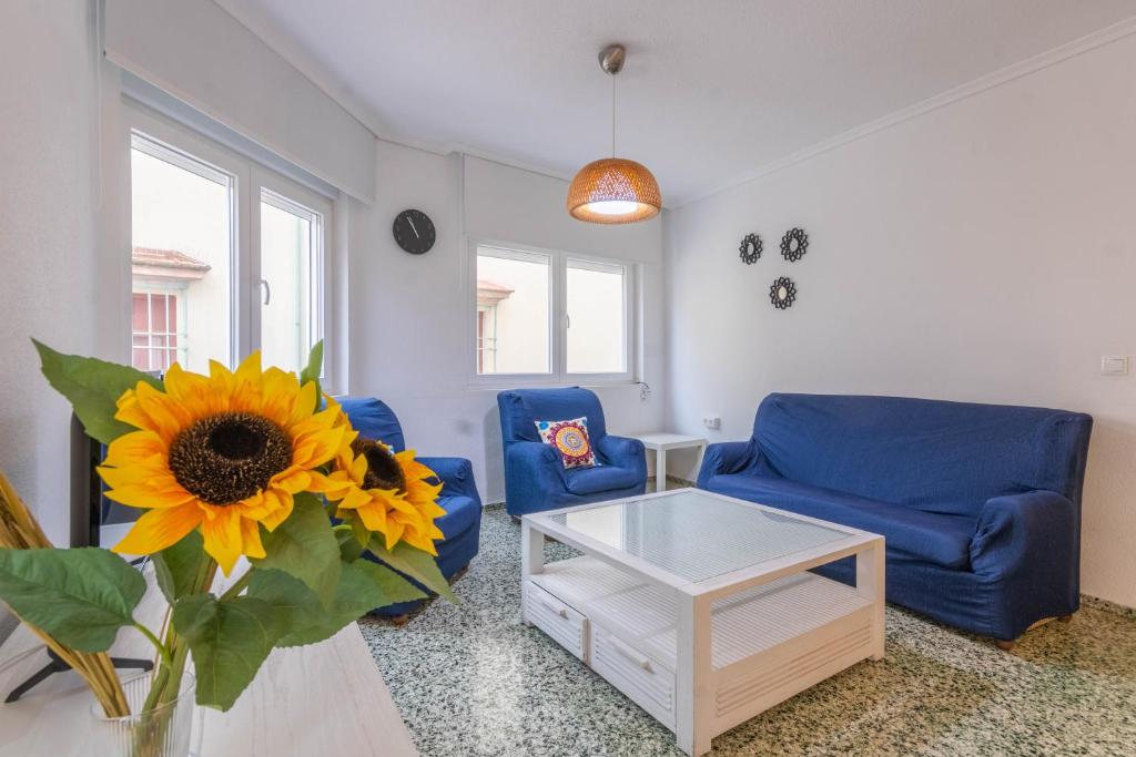 a living room with a blue couch and a table and a sunflower at Apartamento La Alegria de Córdoba Centro in Córdoba