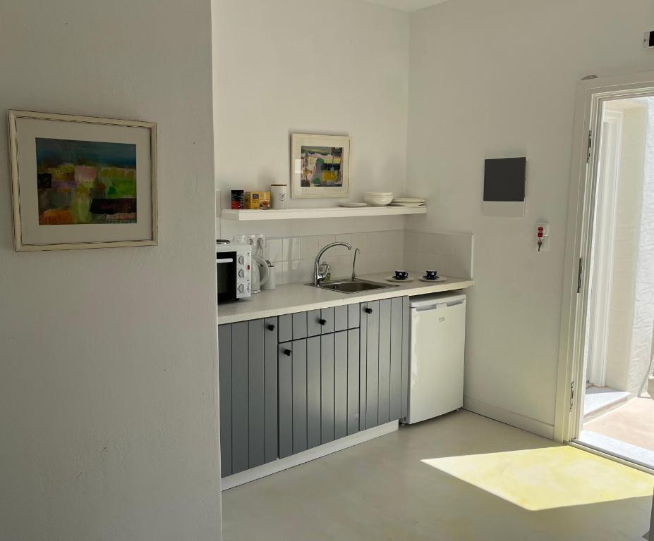 a white kitchen with a sink and a refrigerator at The Black Pig Studios in Posidhonía