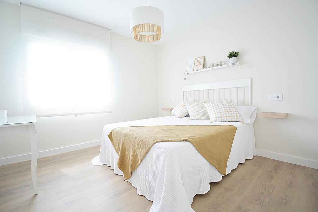 um quarto branco com uma cama branca e uma janela em Apartamento Aires de Lavanda em Sanxenxo