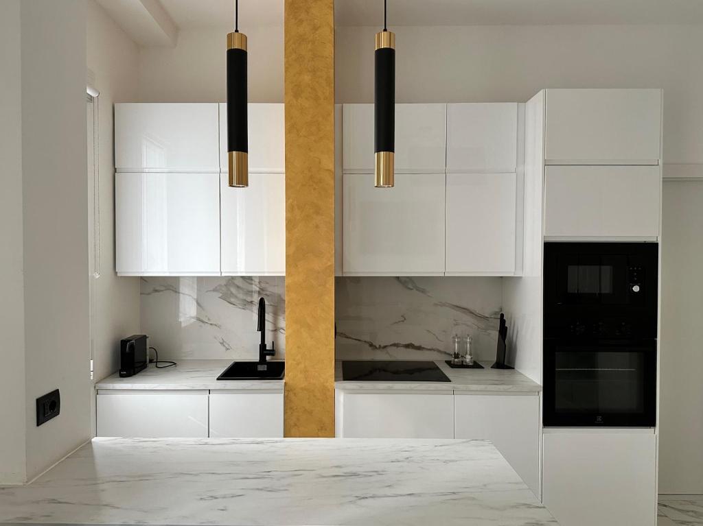 a white kitchen with white cabinets and black appliances at Maison Chanel in Milan