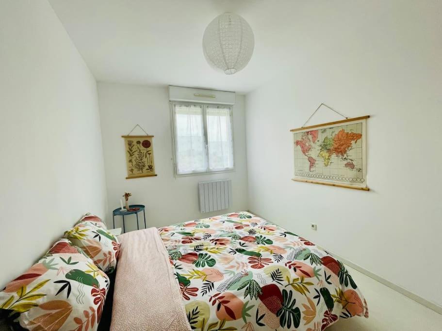 a bedroom with a bed with a floral comforter at Maison entière Domido in Changé