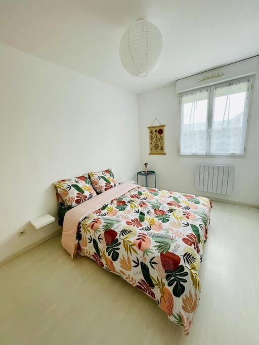 a white bedroom with a bed with a floral bedspread at Maison entière Domido in Changé