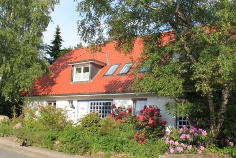 a white house with an orange roof with flowers at Ferienwohnung Amselstieg Dr Meier in Bad Bevensen