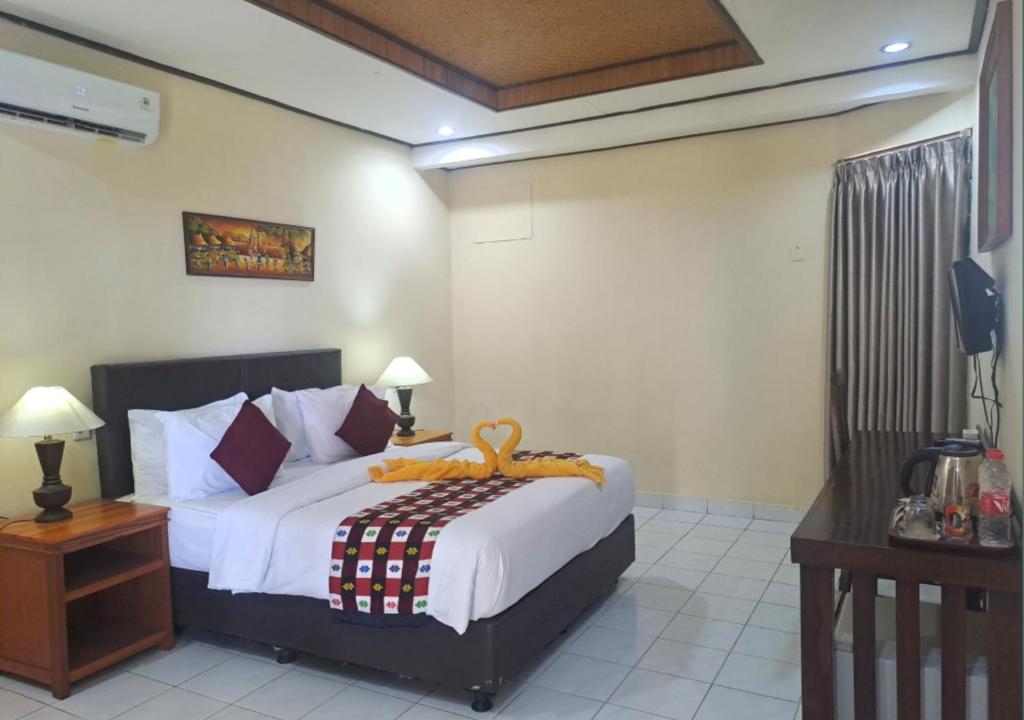 a bedroom with a large bed with white sheets at Lovina Beach Hotel in Lovina