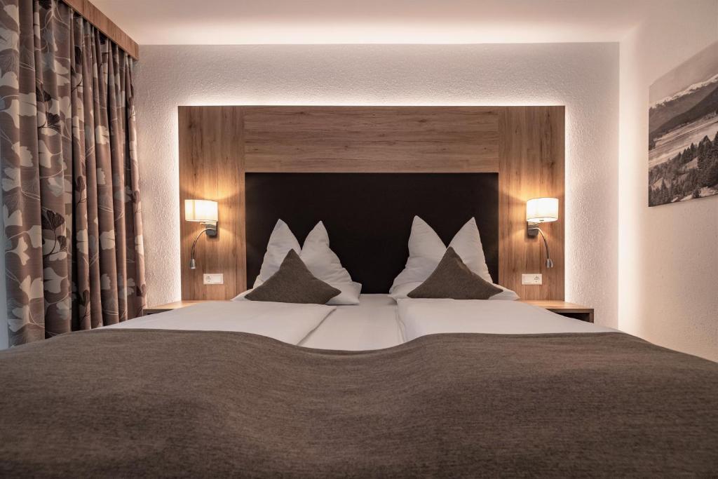 Alpen Adria Hotel & Spa في بريسيغ: غرفة نوم بسرير كبير عليها شراشف ووسائد بيضاء
