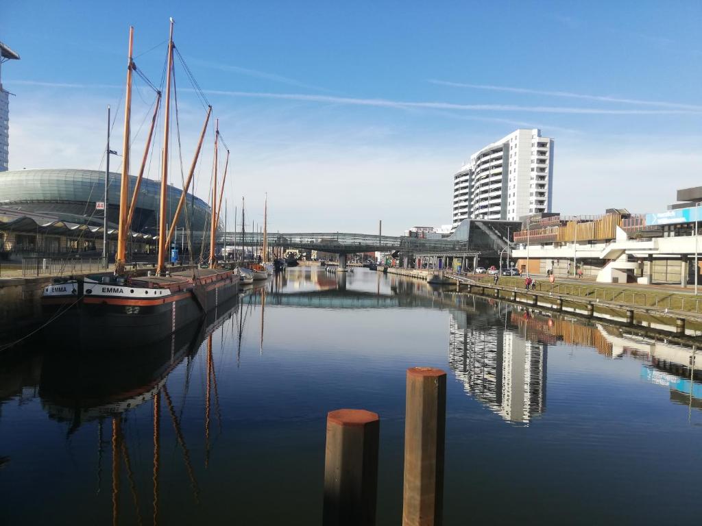 a group of boats docked in a river with buildings at Ferienwohnung Breitschuhs Havenwelten Bremerhaven in Bremerhaven