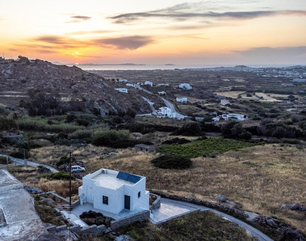 um pôr-do-sol sobre uma pequena casa branca numa colina em Passa Corda Suites with amazing view em Galanádhon