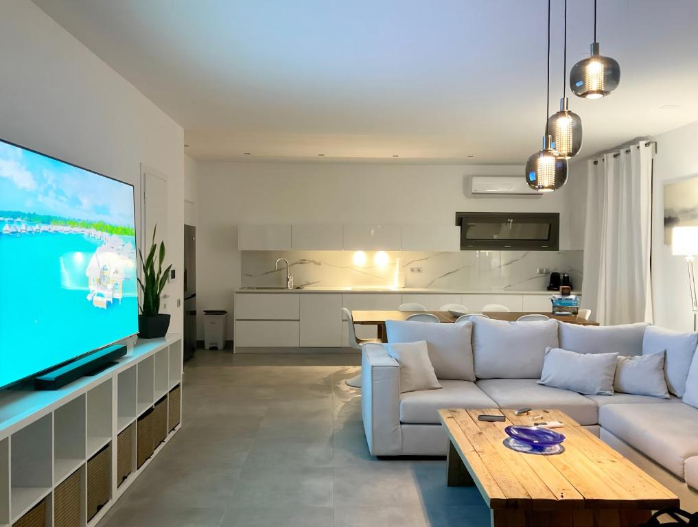 a living room with a white couch and a tv at LUXURY VILLA SEVEN in Skiathos