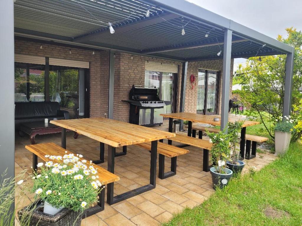 a patio with wooden picnic tables and a grill at Hani's Home Gruppenunterkunft in Verl