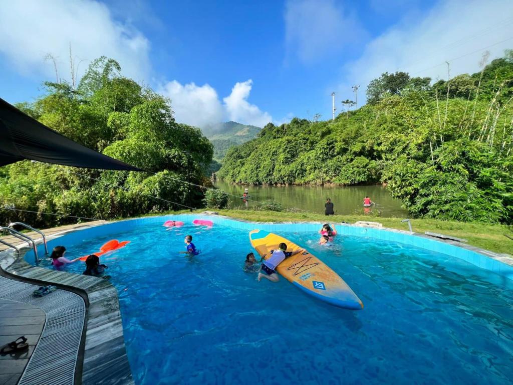 um grupo de pessoas numa piscina com uma prancha de surf em Caofong Glamping Village em Hòa Bình