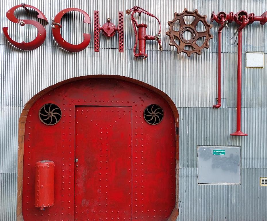 una puerta roja con un cartel en la pared en Schrott Bed&Beer en Brno