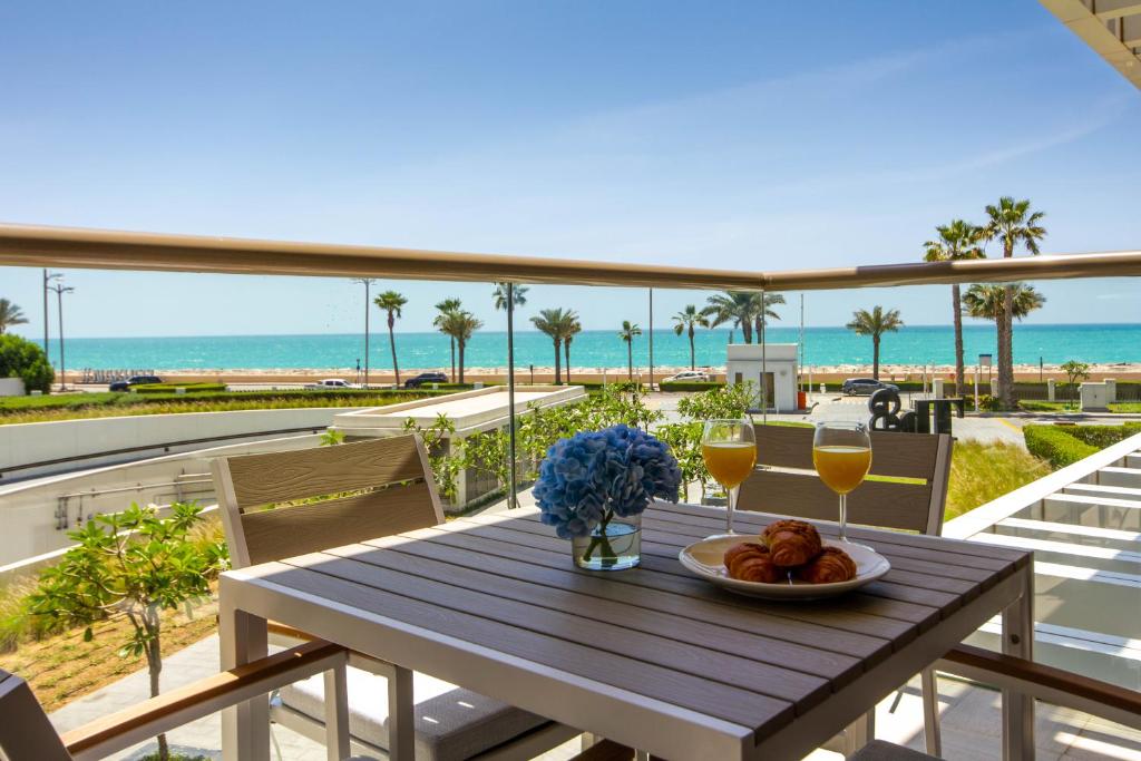 a table with a plate of food on a balcony with the beach at Bespoke Holiday Homes - Palm Jumeirah- 2 Bedroom Sea View with Pool & Beach Access, Th8 in Dubai