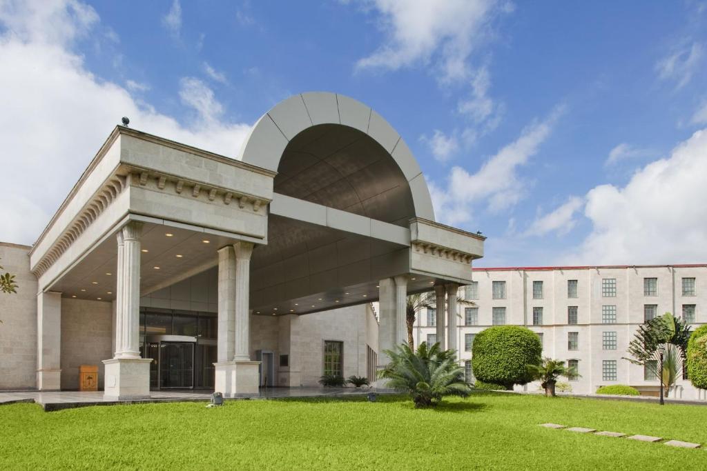 a large white building with a grass field in front at Bisila Palace in Malabo