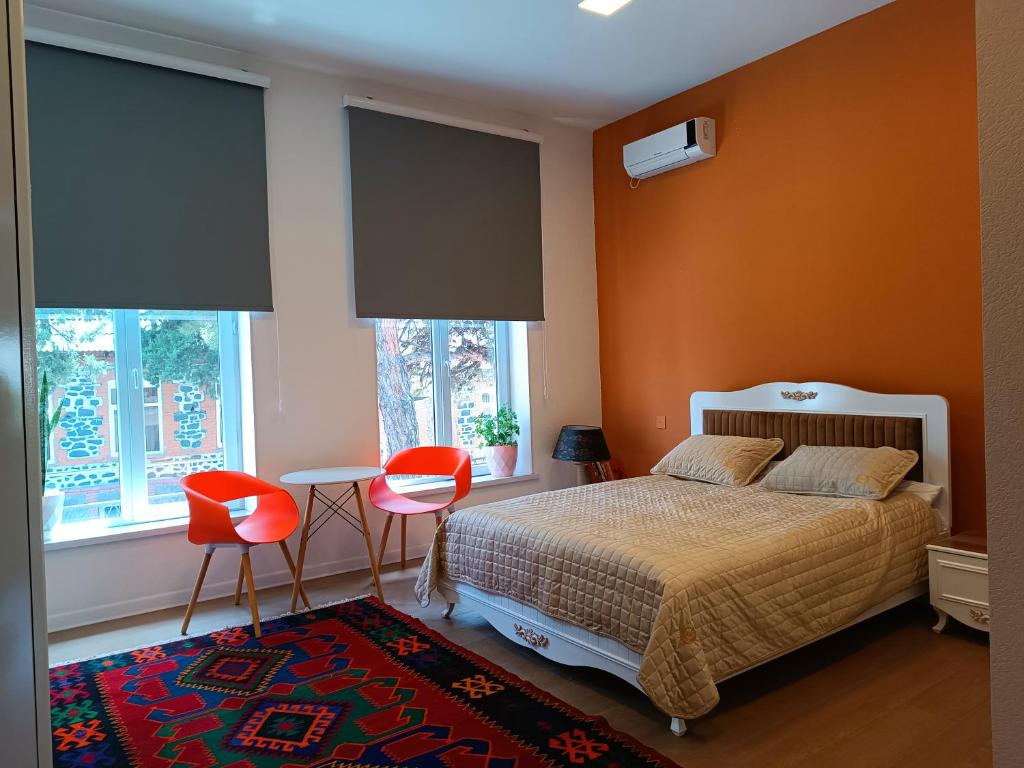 a bedroom with orange walls and a bed and two chairs at Hotel ROUTE 62 in Zaqatala