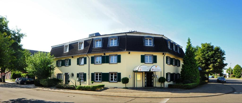 ein großes weißes Gebäude mit schwarzem Dach in der Unterkunft Hotel Pontivy in Wesseling