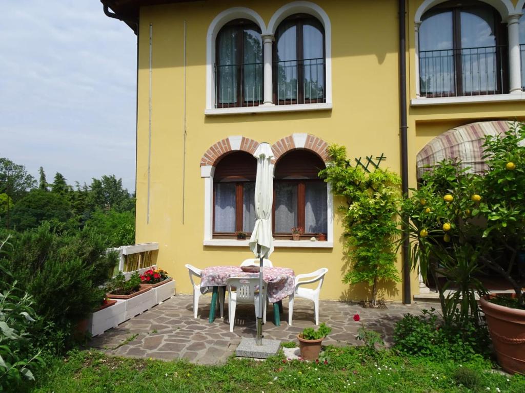 une table et des chaises devant une maison jaune dans l'établissement Appartamento Verdi Colline, à Moniga del Garda