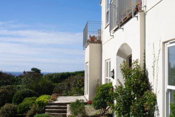a white building with a balcony on the side of it at 3 Linkside, Thurlestone, South Devon, family home close to the beach in Thurlestone
