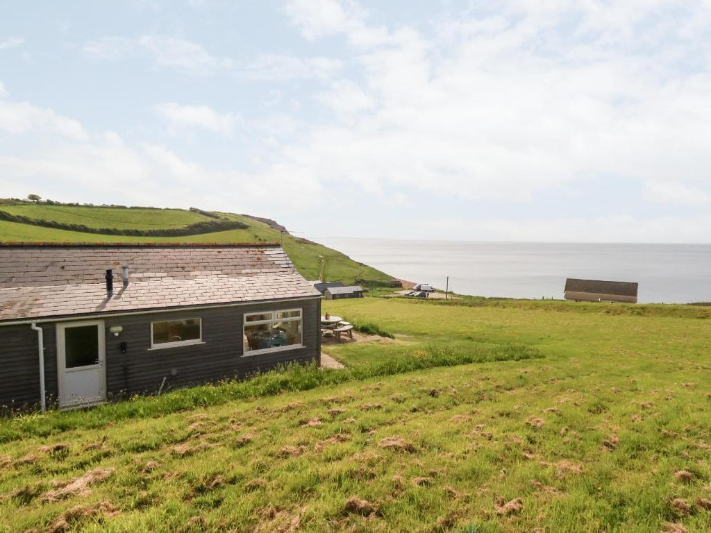 a house on a hill with the ocean in the background at Siesta Chalet in Bridport