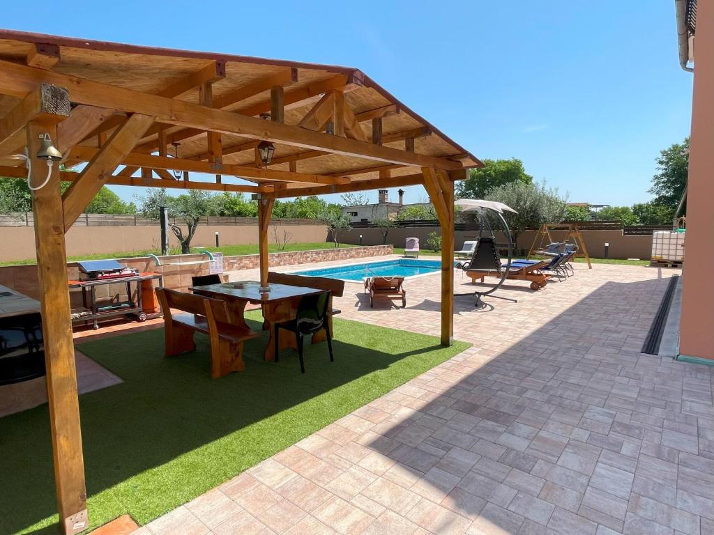 a wooden pavilion with a table and chairs next to a pool at Villa Rosa Apartman in Loborika