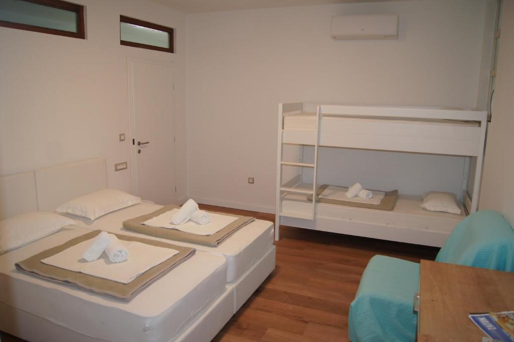 two beds in a room with a table and a chair at Hostel Stadion - Zadar in Zadar