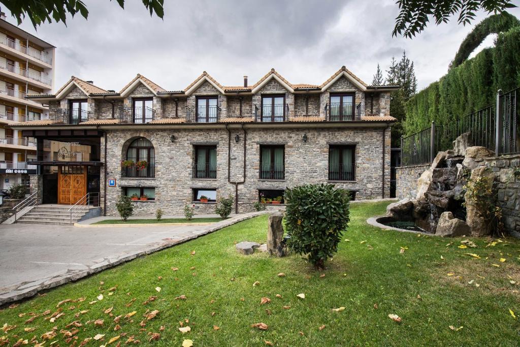 a large brick building with a grass yard in front of it at Hotel Villa Virginia in Sabiñánigo