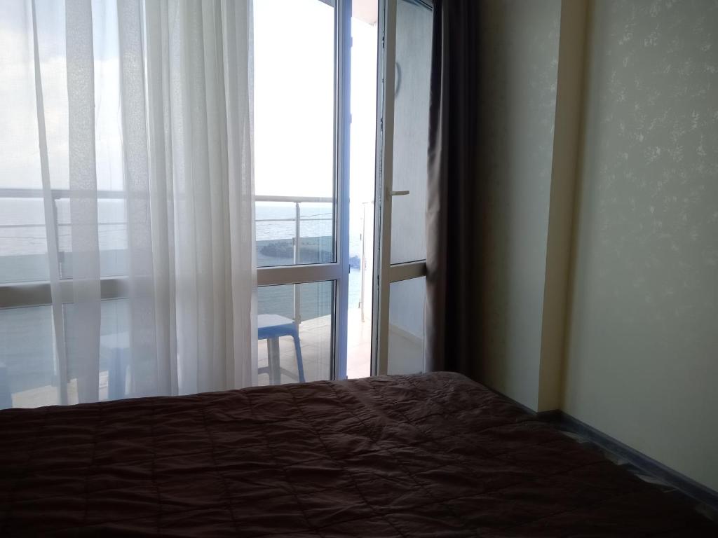 een slaapkamer met een bed en een deur naar een balkon bij СЛЪНЧЕВ ЗАЛИВ in Pomorie