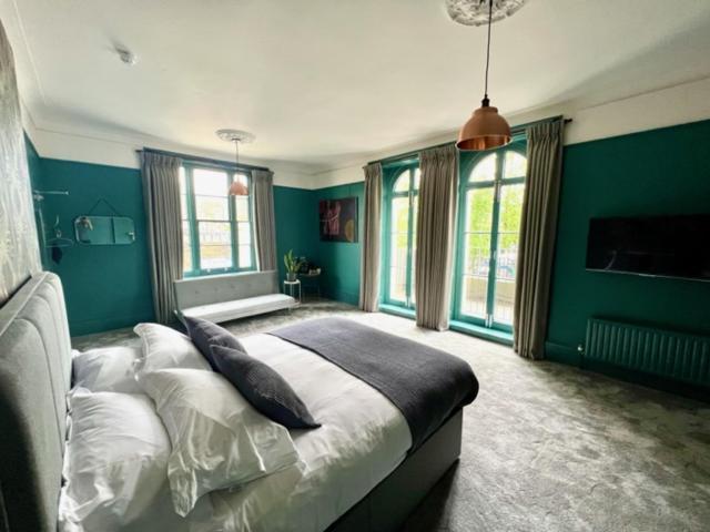 um quarto com paredes verdes e uma cama com almofadas em The Crown Rooms em Londres