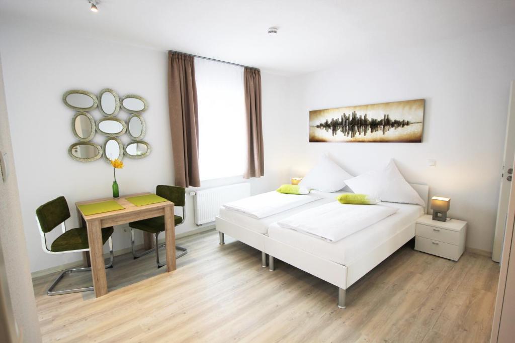 a white bedroom with a bed and a desk at Aparthotel Gartenstadt in Bamberg