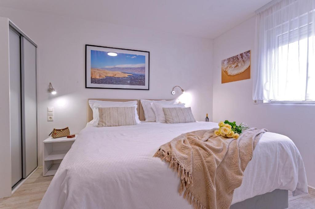 a white bedroom with a large bed with white sheets at Villa Zvonko in Split