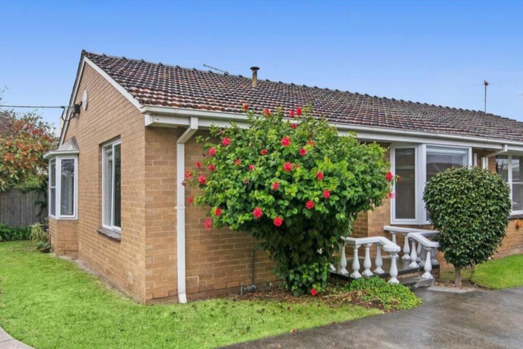 a brick house with a bench and a bush with red roses at Location, Location, Location! Walk to beach & town in Mornington