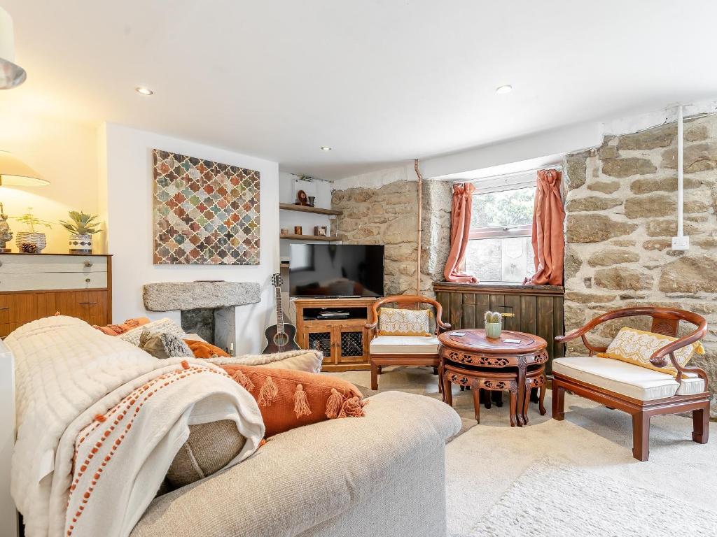 a living room with a couch and a stone wall at Sycamore Cottage in Praze an Beeble
