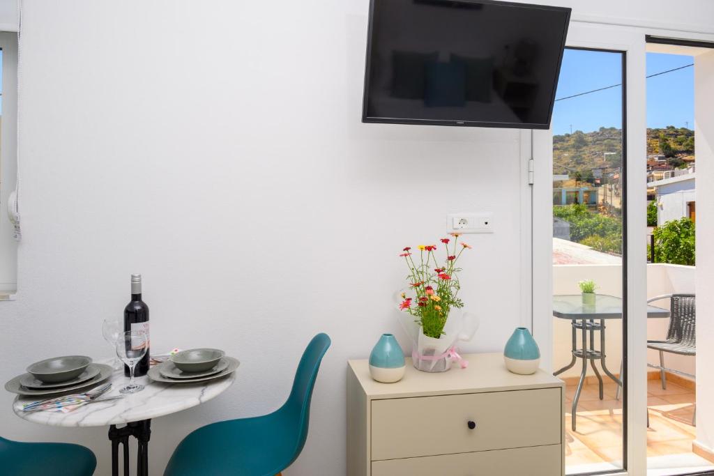 a living room with a table and chairs and a tv at Artemis apartment first floor in Elounda