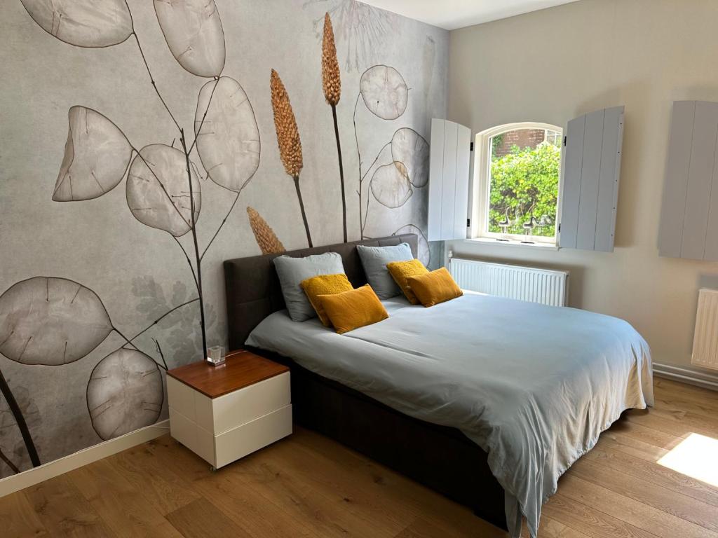 Koetshuys van Villadelfia في Tynaarlo: غرفة نوم بسرير وجدار مع جدارية ورد
