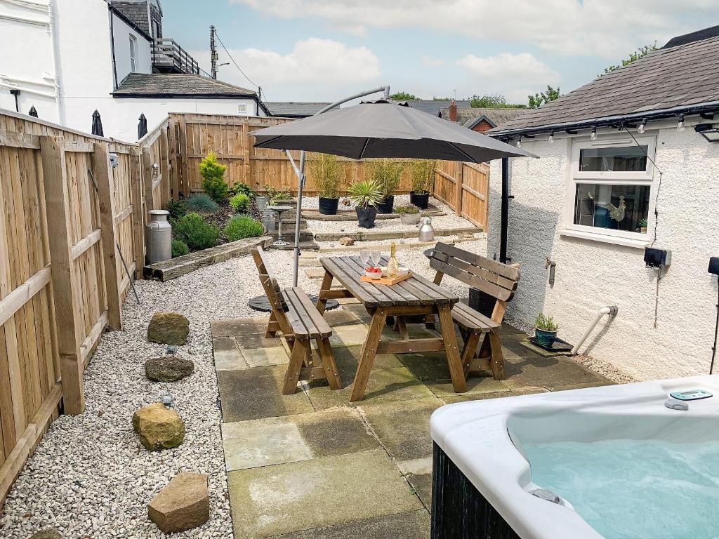a patio with a table and an umbrella and a tub at No 1 Overman in Bowburn