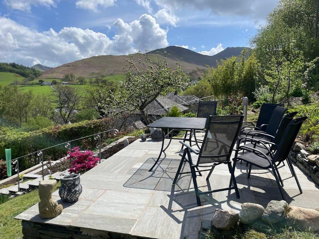 a table and chairs on a patio with mountains in the background at Three Peaks in Braithwaite