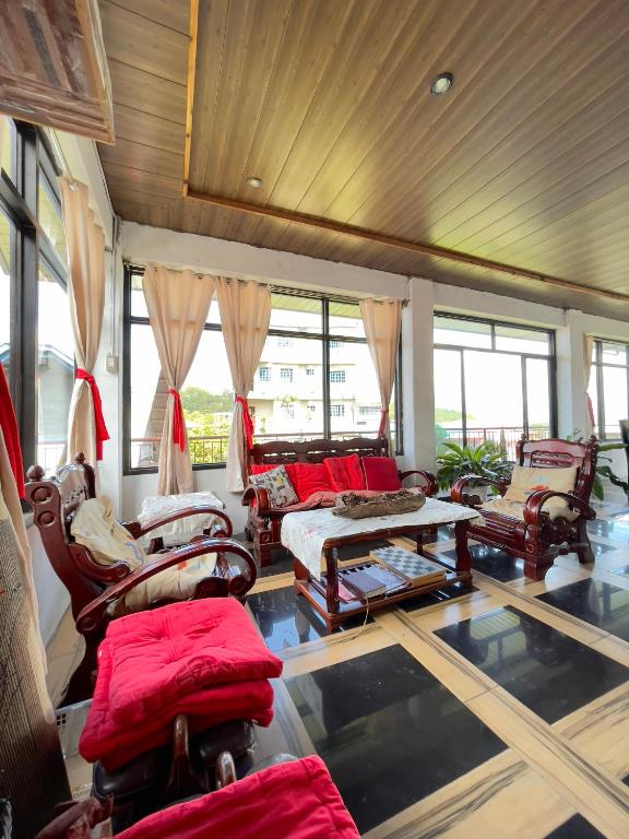 a living room with chairs and tables and windows at Andrew & Mary's Lodging House in Sagada