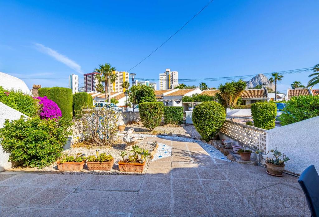 Un jardín con plantas en macetas, árboles y edificios. en Inftour La viña Bungalow, en Calpe