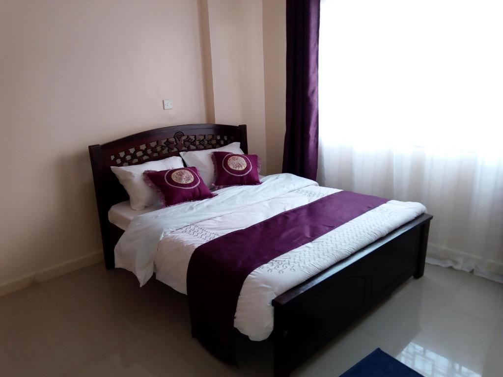 Un dormitorio con una cama con almohadas moradas y una ventana en Captivating 3-Bed Apartment in Nairobi Kenya, en Nairobi