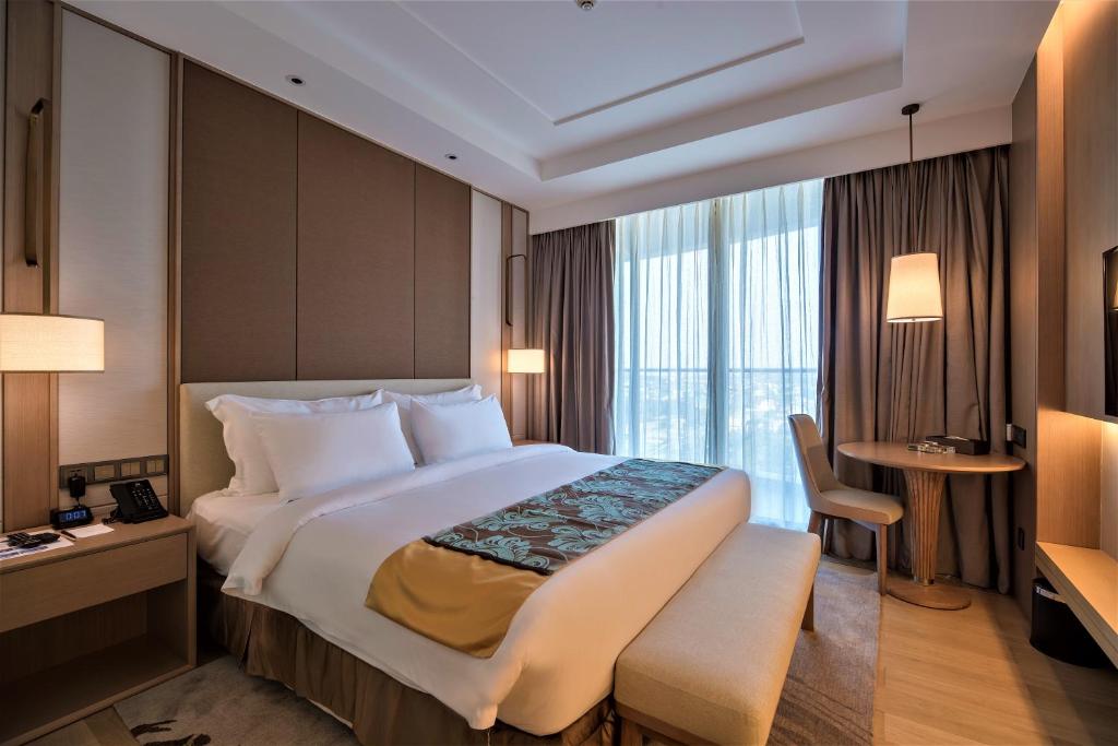 シアヌークビルにあるJing Shang Hotelの大きなベッドとデスクが備わるホテルルームです。