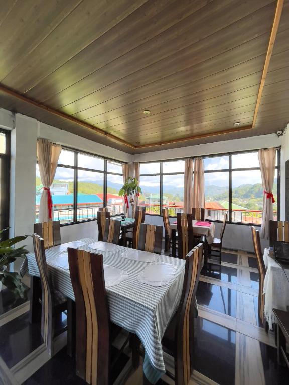 a dining room with tables and chairs and windows at Andrew & Mary's Lodging House in Sagada